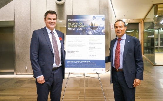 Two people standing beside a sign for Centre for Customer Centricity at Schulich School of Business